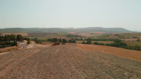 Scenic Landscape Of San Quirico D'Orcia With Tourists Walking During Summer In Italy - aerial drone shot
