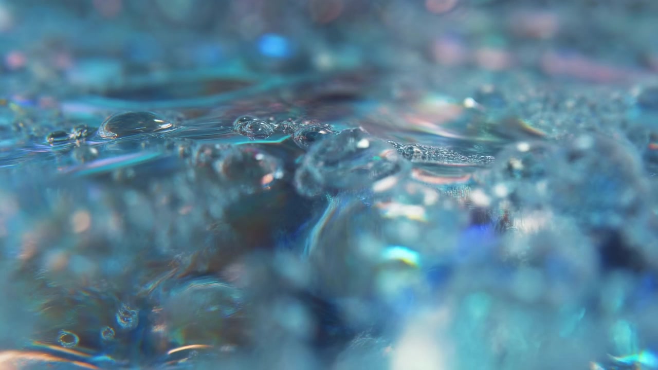 Scène en contre-plongée montrant des gouttelettes d'eau sphériques claires et de minuscules bulles reposant sur une surface aquatique brillante, avec des reflets lisses, une faible profondeur de champ, une lumière irisée et des accents de couleurs pastel douces