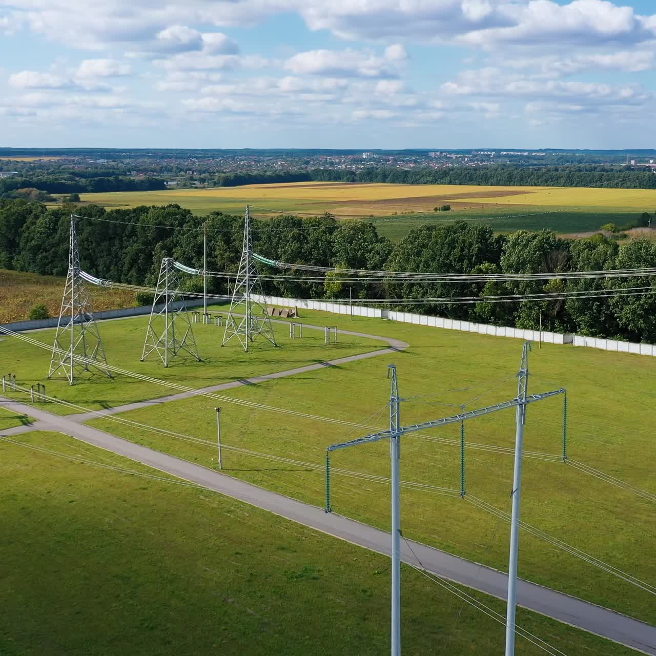 Electric transmission towers on a green field. Power lines supply with wires. High voltage electric pylons in the countryside