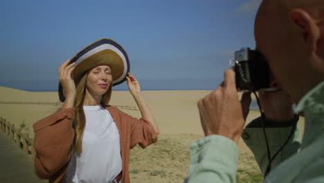 man photographing attractive girlfriend on beach