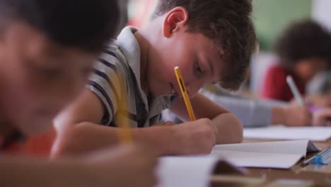 dos niños escribiendo mientras están sentados en su escritorio en la escuela