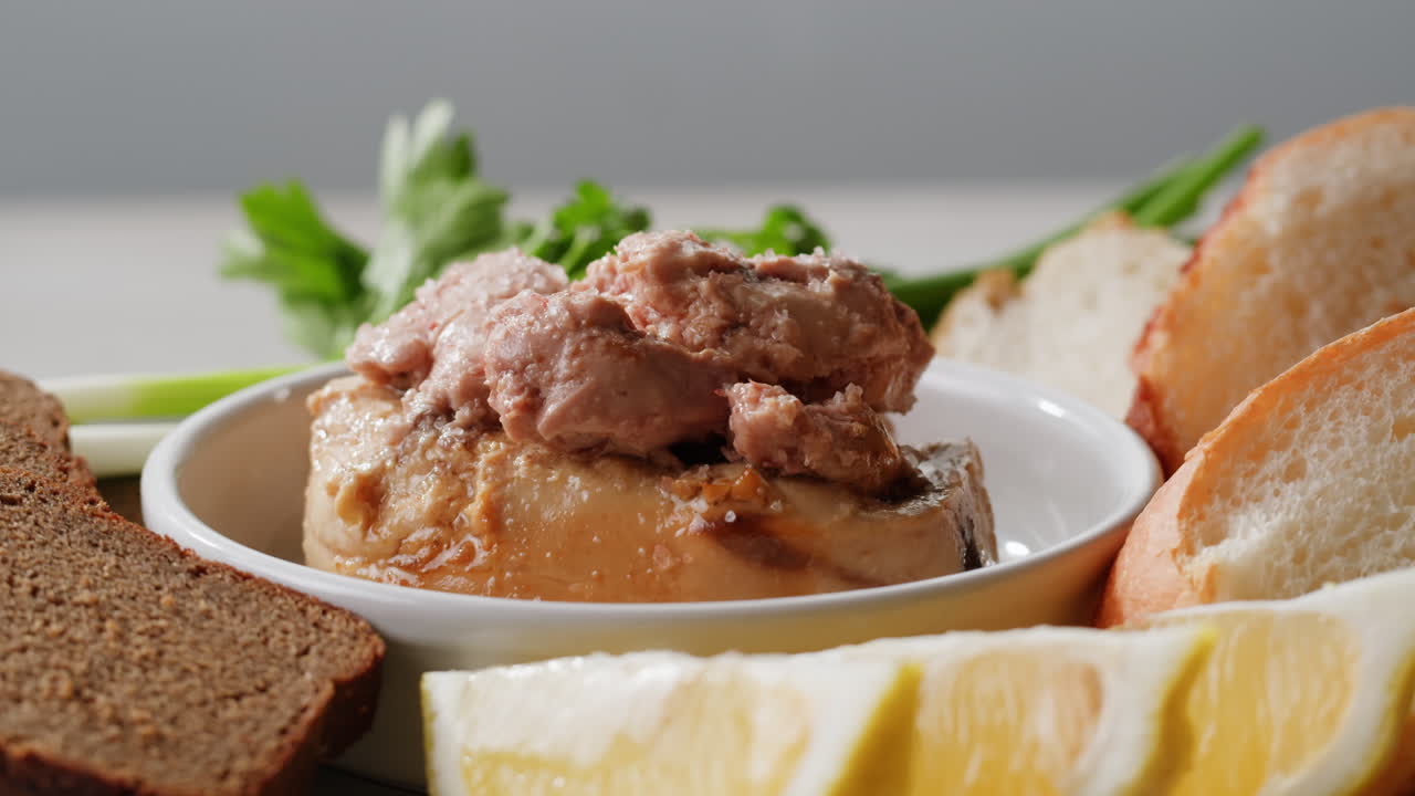 Smoked cod liver in oil in open tin can with fresh greens on wooden table. Seafoods delicacy. High quality 4k footage