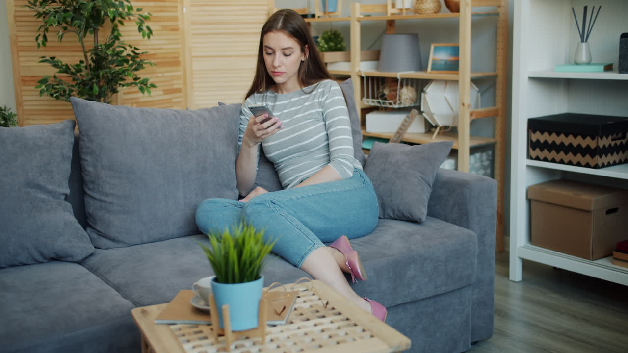 Woman using smartphone on a sofa at home