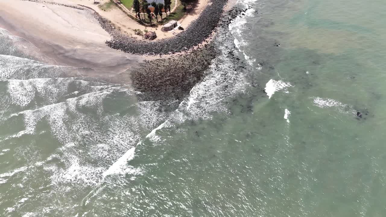 Drone shot of a sandy peninsula in Banjul, Gambia, where the Atlantic Ocean waves meet along the coast
