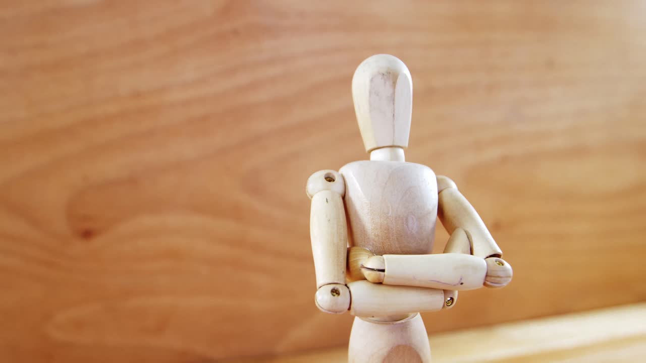 estatuilla de pie con los brazos cruzados en un piso de madera