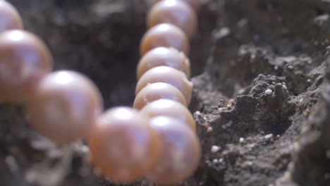 toma cinematográfica que se mueve a lo largo de un collar de perlas naturales sobre una roca natural en una playa, slomo, 120 fps