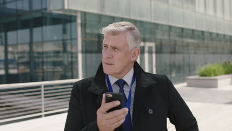 portrait of corporate businessman boss texting networking using smartphone looking serious pensive in urban city background