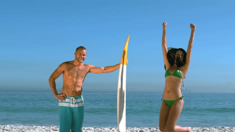 Attractive-girl-jumping-next-to-a-friend-with-a-surfboard