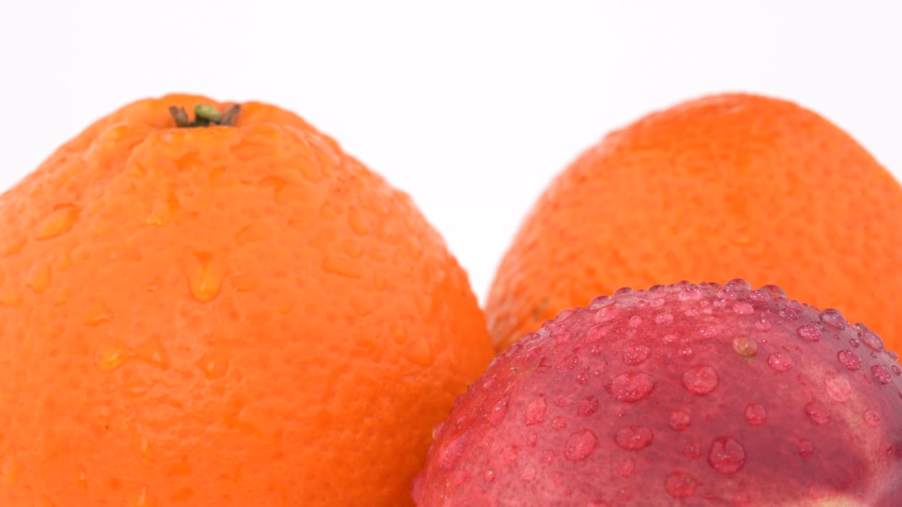 macro (extremo de cerca) de jugosas frutas de naranja, mandarina y nectarina con gotas de agua girando sobre un fondo blanco. aislado. de cerca.