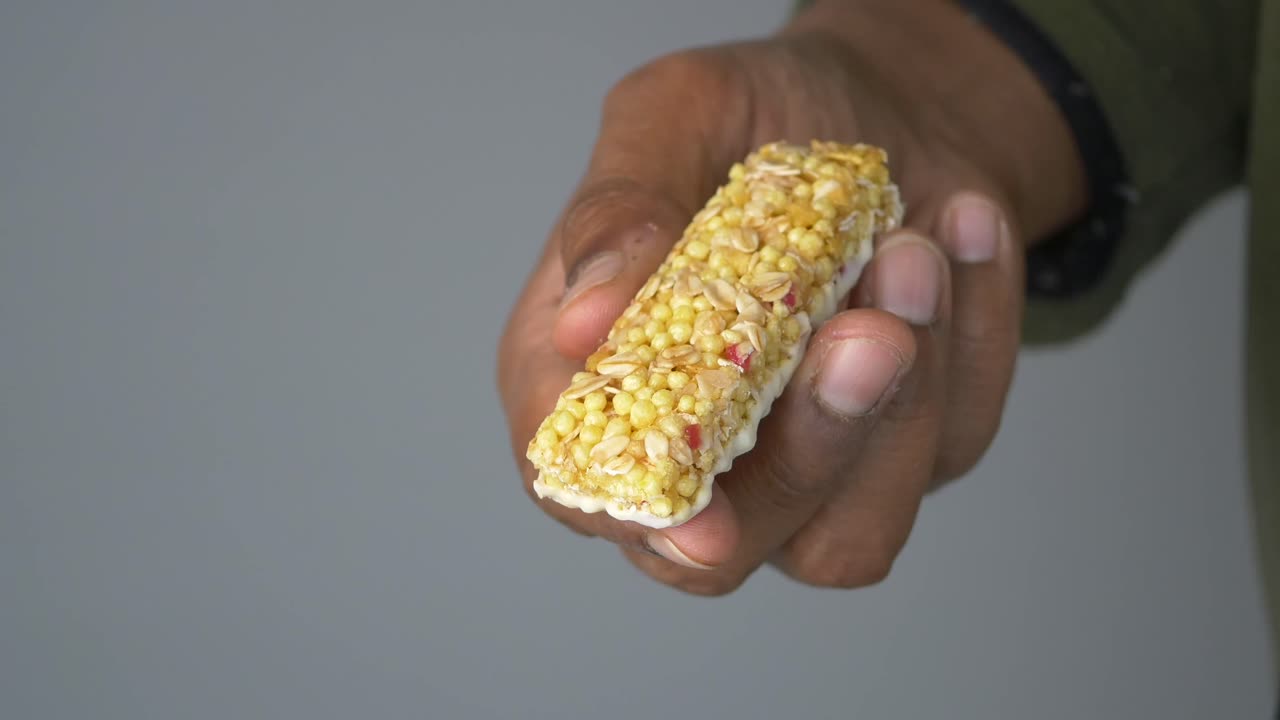 Nahaufnahme einer Hand, die einen Müsliriegel hält