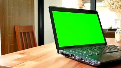 dolly shot: laptop computer with green screen for chroma key on wooden table in cafe, restaurant, or home