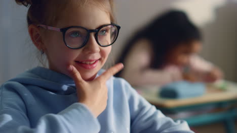 Smiling-pupil-learning-at-school.-Thoughtful-schoolgirl-holding-hand-on-chin