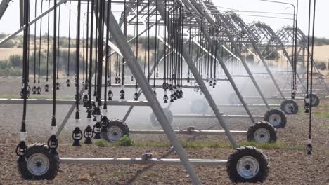 close up wheel of pivot at work in potato field, watering crop for growth