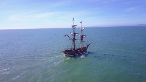 spectacular aerial following a tall sailing ship on the open ocean by day