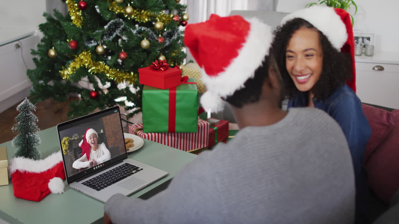 feliz pareja afroamericana en videollamada en computadora portátil con amiga en tiempo de navidad