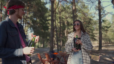 Eine-Junge-Frau-Gibt-Zwei-Männlichen-Freunden,-Die-Auf-Dem-Land-Grillen,-Flaschen-Bier.-Menschen-Genießen-Ein-Picknick-In-Der-Natur.