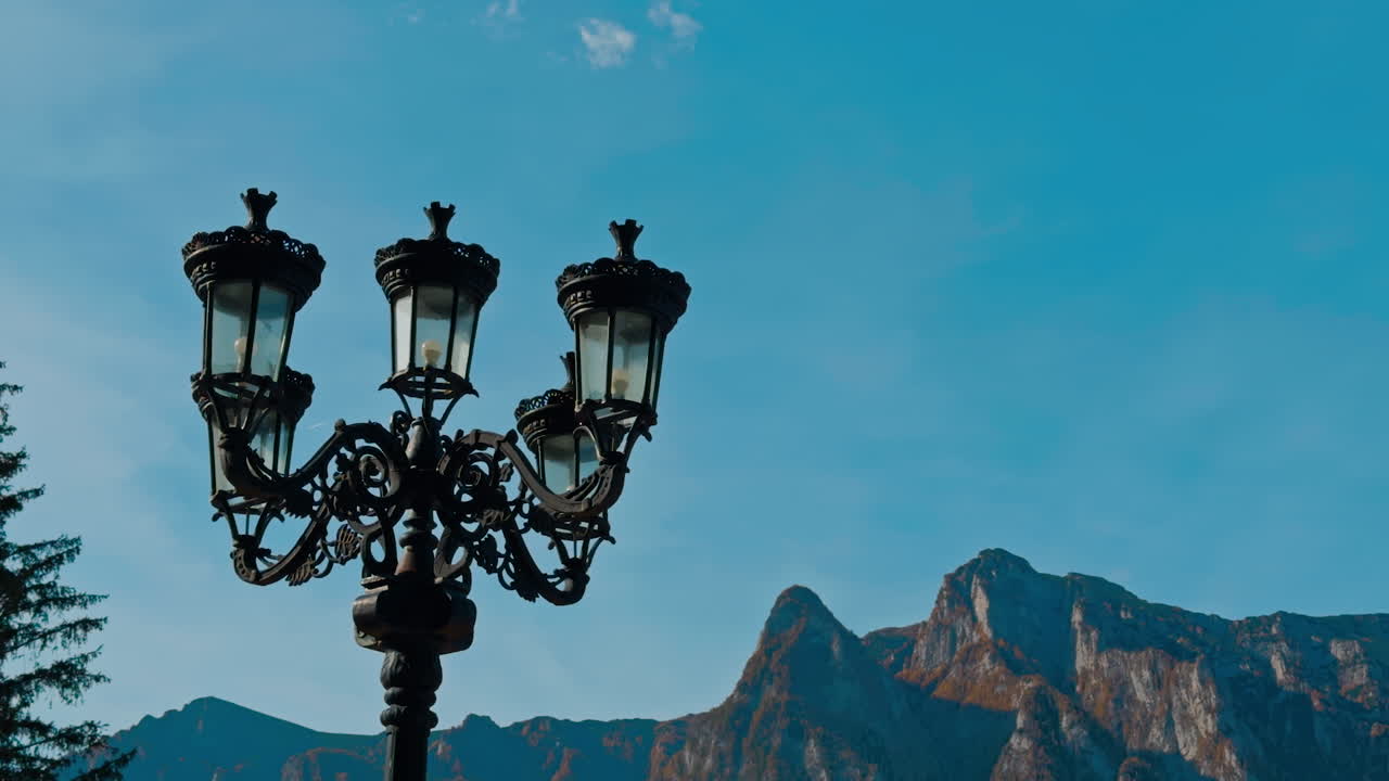 Beautiful black old-style street lantern. Autumn nature and hazy mountains at backdrop.