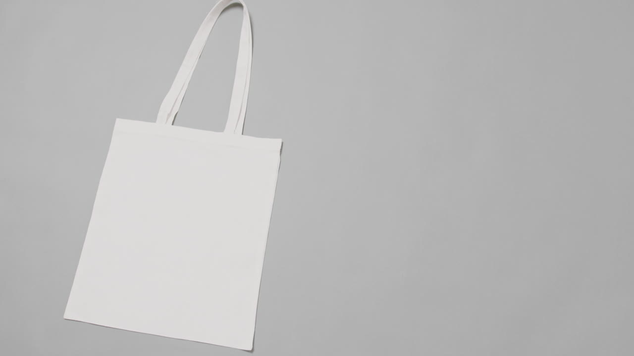 Primo piano di borsa bianca su sfondo grigio, con spazio per il testo, in slow motion