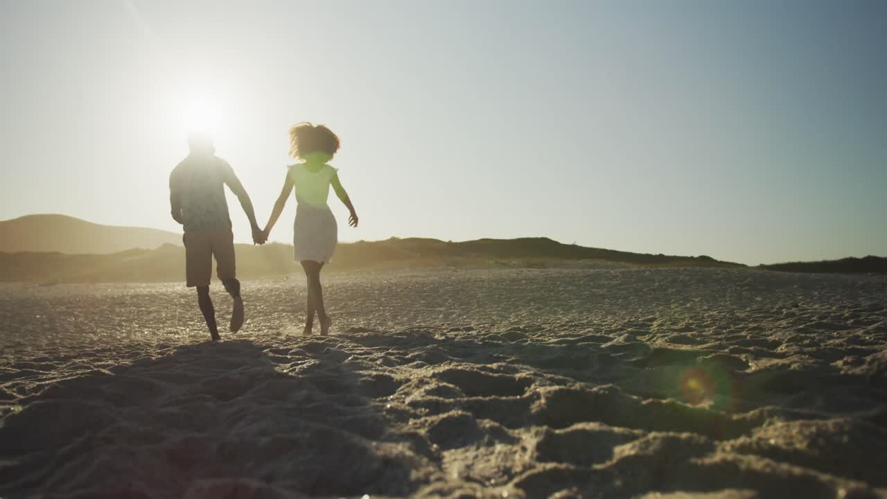 African American couple running side by side at beach