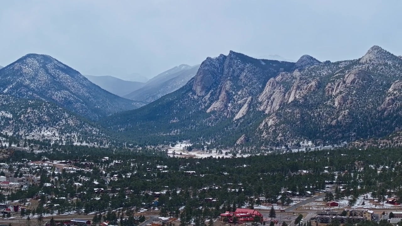 Area residenziale di Estes Park con foresta e Montagne Rocciose in condizioni invernali, panoramica aerea con drone
