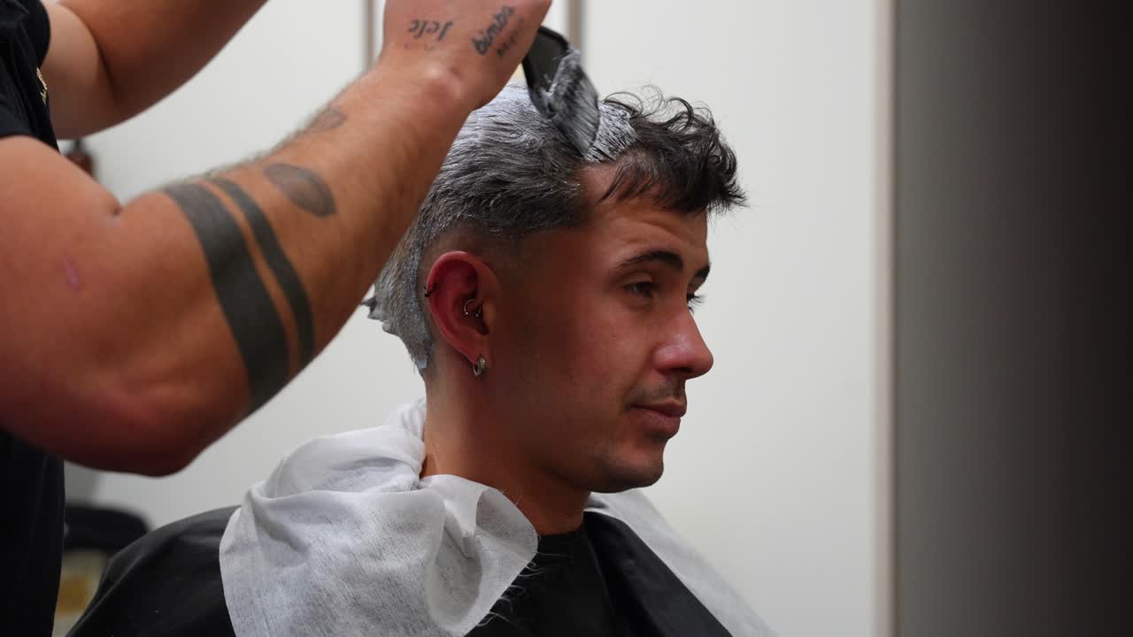 Customer chats with barber while getting first bleaching powder and oxidant treatment applied