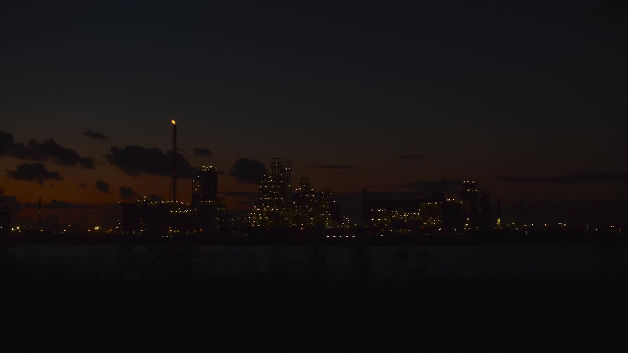 낮부터 밤까지 시간 경과에 보트가 지나가는 스켈데 강 옆에 있는 앤트워프 항구의 산업 건물