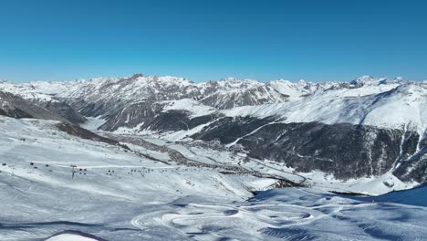 aerial view of italian alps and ski lift above livigno town on sunny winter day, drone shot