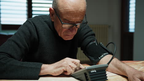 elderly man measures his blood pressure at home