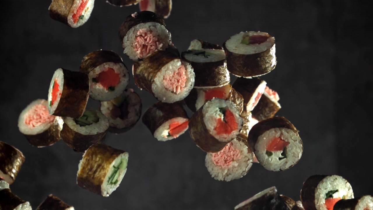 Verschiedene Sushi-Rollen fallen und schweben in Zeitlupe.