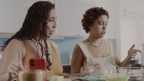 two women cooking and preparing food in a kitchen, possibly recording an online tutorial