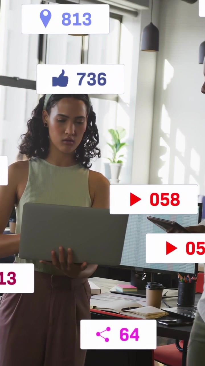 Vertical video: Woman with laptop reviewing social metrics, causing icons swelling then settling