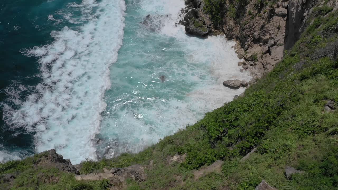 Man looking down cliff at Diamond beach, Aerial, tilt down, Bali