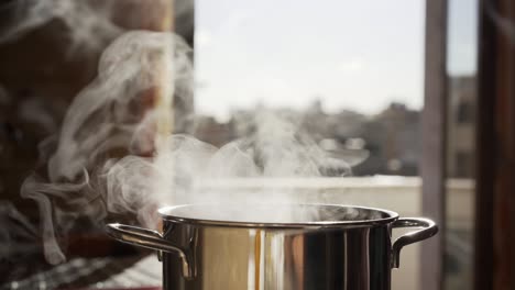 boiling stainless pan under high temperature. white steam rising from the pot and vaporing in the air. steamy pot in clean kitchen. natural effects under high temperature