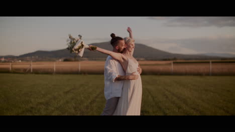 couple dancing in field at sunset