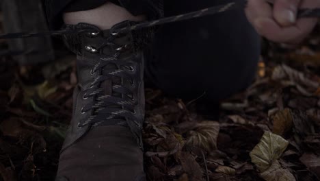 hiker tying boot laces in autumn leaves close up shot