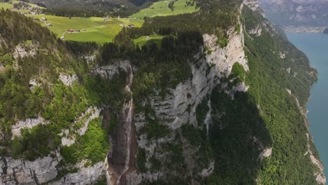 seerenbach falls flowing through tall cliffs in betlis, switzerland. drone scenic view of swiss meadows, pine forests and rocky mountains on bright day