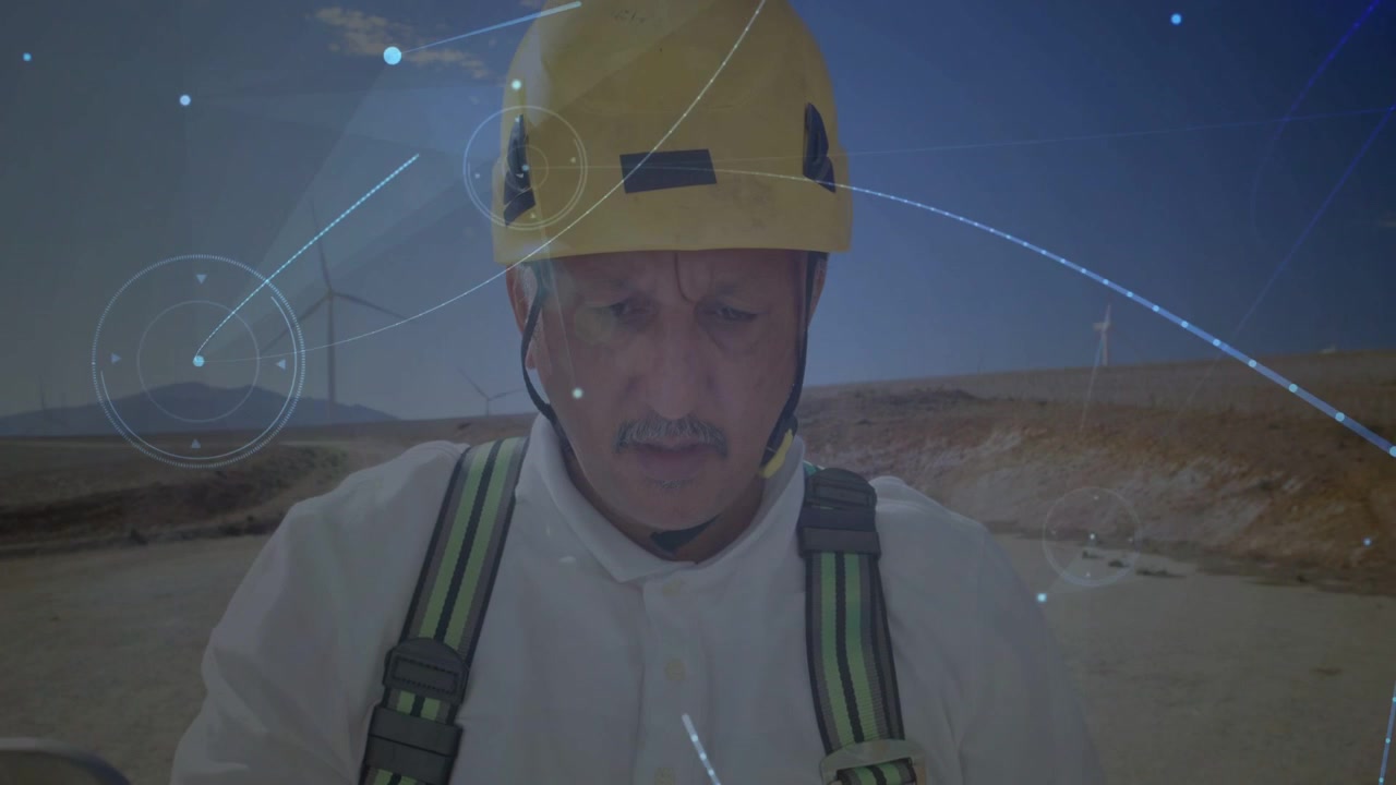Technician wearing yellow hard hat white coverall checking harness and radio on arid plain with HUD