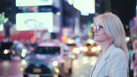 a woman stands in times square in new york recognizable yellow taxis are passing by - a symbol of th