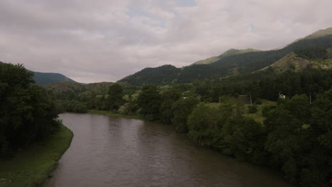 Idyllic-River-With-Lush-Woody-Plants-And-Caucasus-Mountain-Range-At-Background-In-Georgia