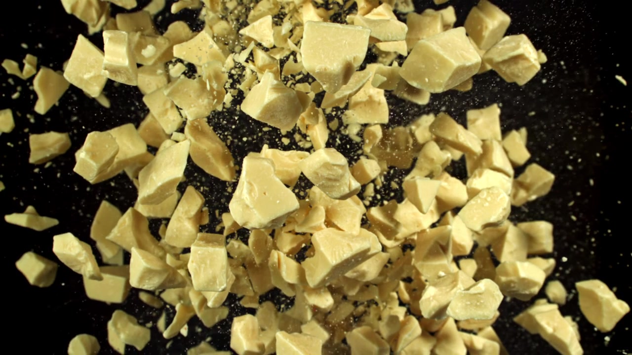 Deliziosi pezzi di cioccolato bianco in caduta su sfondo nero
