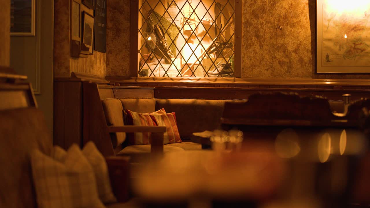 Cozy pub booth with warm lighting, wooden decor, patterned cushions, and soft bokeh background