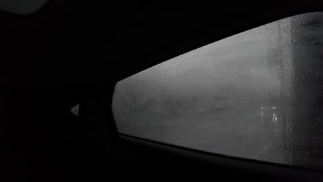 View-from-inside-dark-car,-condense-fog-on-window,-raining,-cars-passing