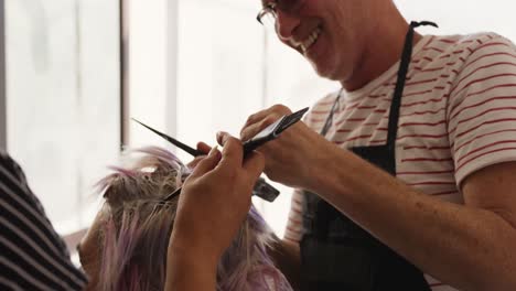 vista cercana de una mujer que tiene su cabello estilizado por dos peluqueros