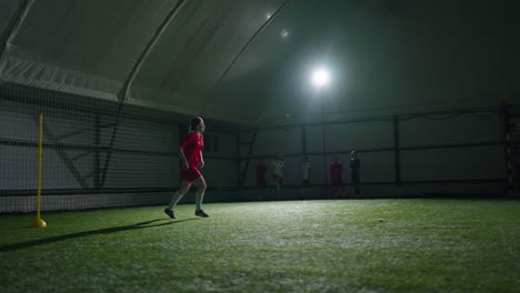soccer player training indoors with other players watching