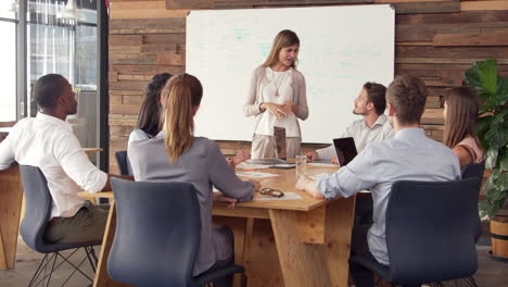 young white woman giving presentation to business colleagues