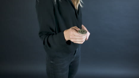 young blonde woman flipping a gold bitcoin coin,catching it,detail