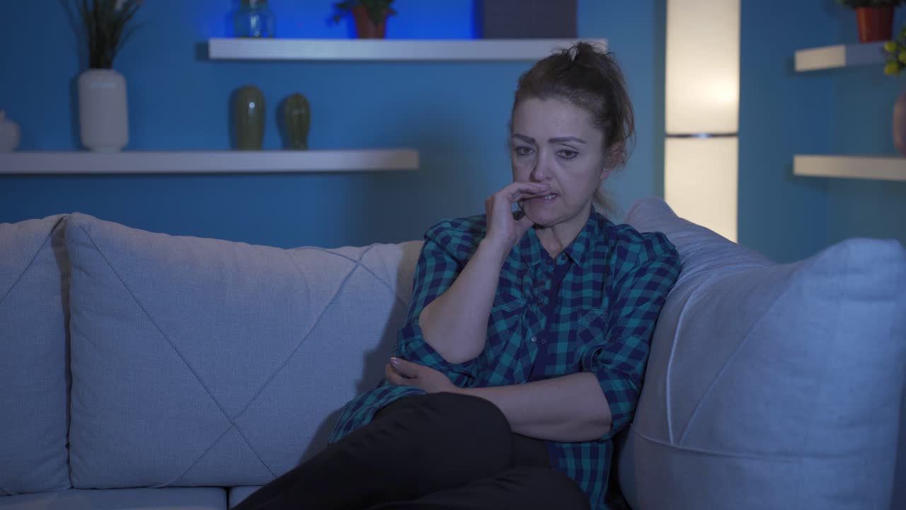 Woman biting her nails because of stress at home at night.