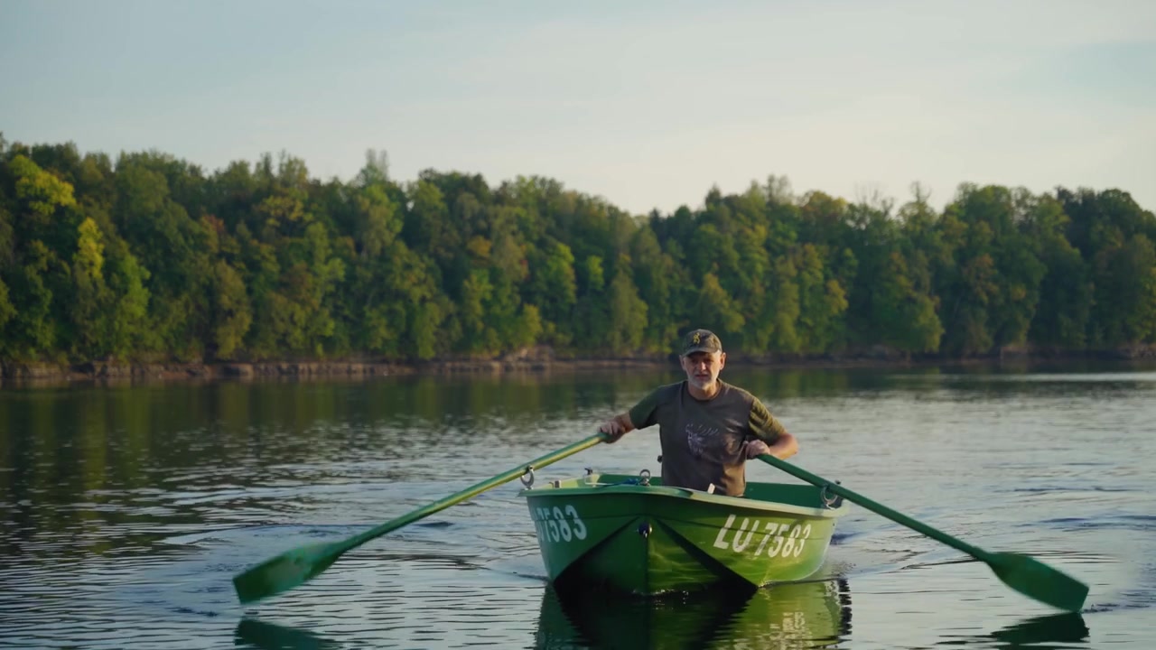 Senior men rowing a boat in the river towards the camera.