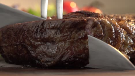 extreme close up shot on piece of steak cutting using a kitchen knife and barbecue fork