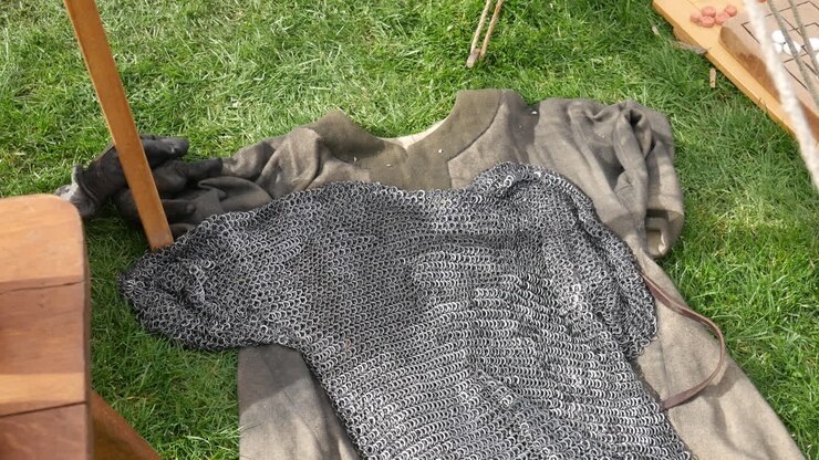Chainmail armor spread on a cloth on grass, evoking medieval viking warfare and knight gladiator battle attire